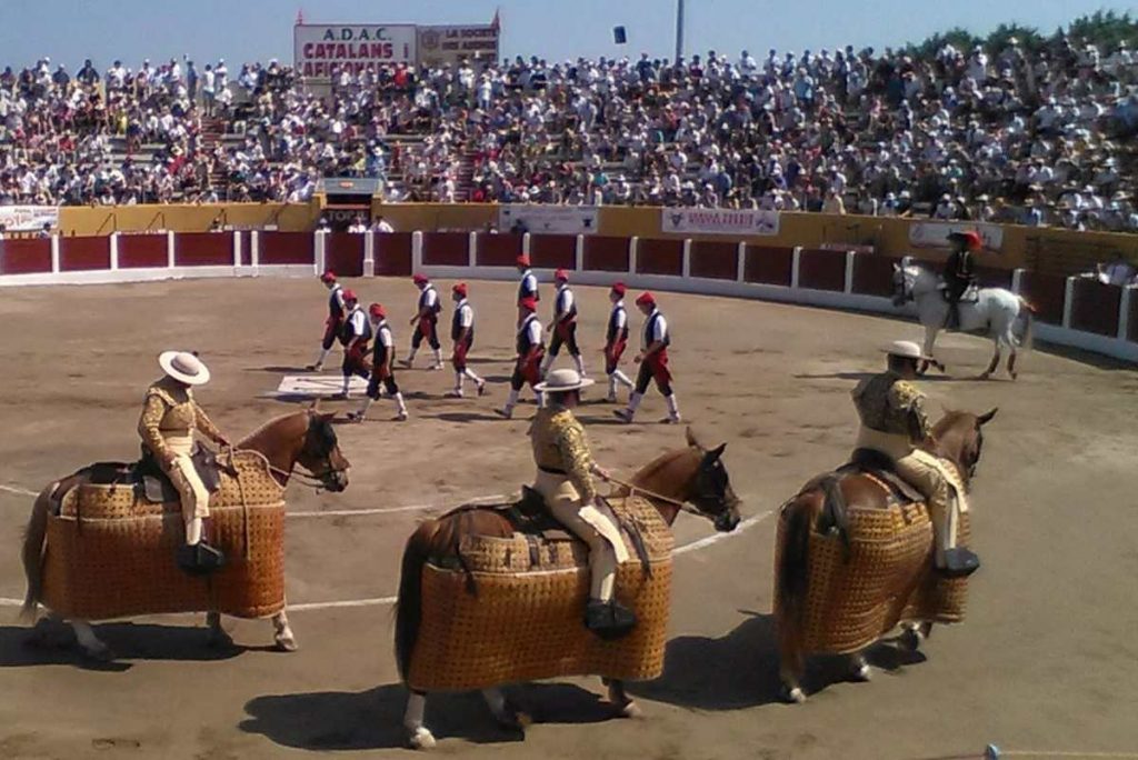 Corrida avec chevaux et matadors en arène bondée.