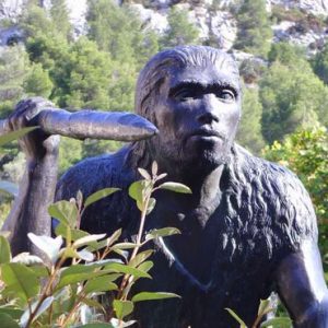 Statue préhistorique avec outil parmi les arbres