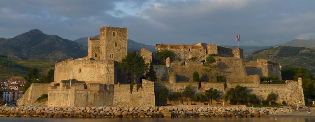 Château médiéval dans paysage montagneux ensoleillé.