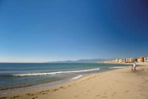 Plage de sable avec horizon et immeubles en arrière-plan.