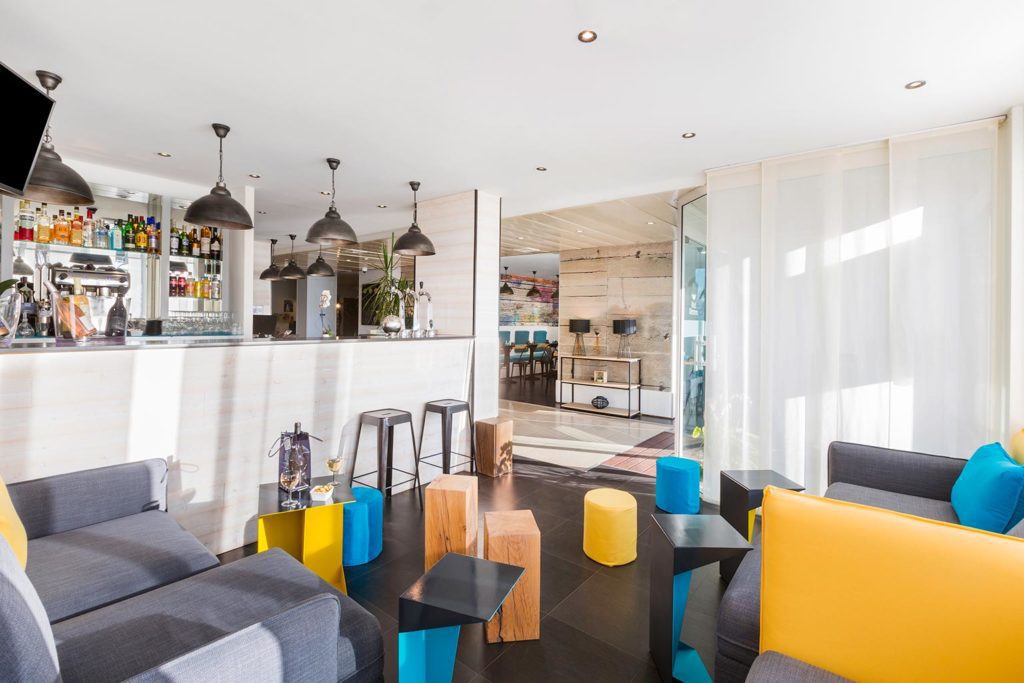 Salon moderne avec bar et sièges colorés.