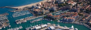 Vue aérienne sur port de plaisance et plage méditerranéenne.